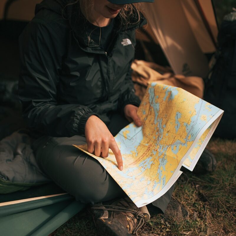 person wearing The North Face jacket sitting on sofa while holding map